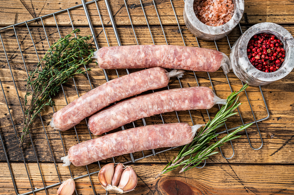 Raw Sausages - Bratwurst with Pork Meat on a Griil. Wooden Backg